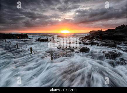 Schwere See mit großen Wellen und einem rosa Himmel bei Sonnenaufgang über Kiama Felsenpool, Kiama, Illawarra Coast, New-South.Wales, NSW, Australien Stockfoto