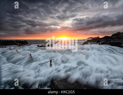 Schwere See mit großen Wellen und einem rosa Himmel bei Sonnenaufgang über Kiama Felsenpool, Kiama, Illawarra Coast, New-South.Wales, NSW, Australien Stockfoto