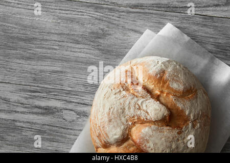 Hausgemachte Handwerker Sauerteig Roggenbrot über weißen hölzernen Hintergrund. Draufsicht des Brotes auf Kochpergament vertreten. Leere Kopie Raum für Ihre Id in Anbetracht Stockfoto