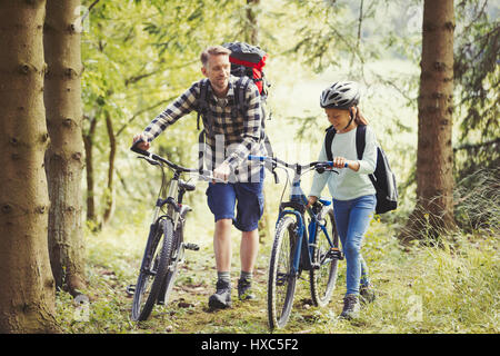 Vater und Tochter mit Rucksäcke Wandern Mountain-Bikes in Wäldern Stockfoto