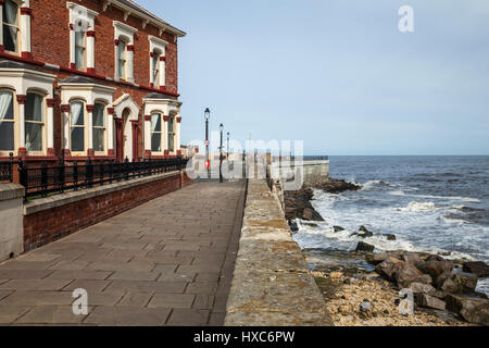 Die Strandpromenade und die Häuser bei Hartlepool Landzunge, England, UK, mit den Wellen, die gegen die Felsen Stockfoto