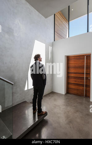Nachdenklich Geschäftsmann im modernen home Schaufenster innere Foyer stehen Stockfoto