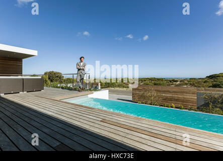 Geschäftsmann auf moderne, luxuriöse Sonnenterrasse mit Infinity-pool Stockfoto