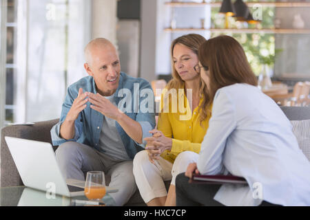 Finanzberater mit Laptop Treffen mit paar im Wohnzimmer Stockfoto