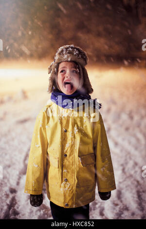 Junge in warme Kleidung, die Zunge heraus, Verkostung Schnee Stockfoto