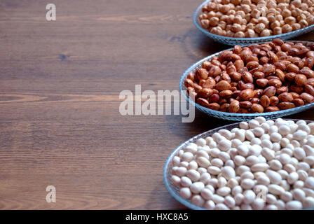 Impulse in einer Schüssel auf einem Holztisch für Bacgrounds (Gartenbohnen Bohnen, Kidney-Bohnen und Kichererbsen) Stockfoto