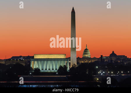 Das Lincoln Memorial, Washington Monument und US Capitol Gebäude gesetzt gegen einen orangefarbenen Himmel während der Morgendämmerung in Washington, DC. Stockfoto