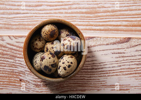 Wachteleier in eine kleine Schüssel mit Nest Form auf weißen Holzbrett Stockfoto