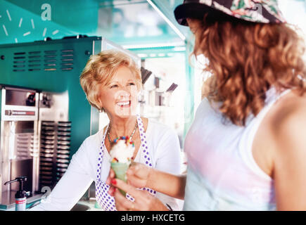 Lächelnd älterer weiblicher Unternehmer mit Eis zu junge Frau an Nahrungsmittel Warenkorb Stockfoto