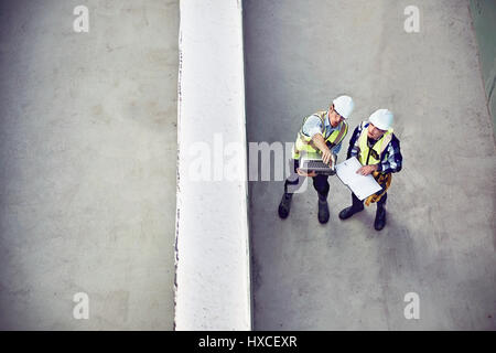 Bauarbeiter und Ingenieur mit Laptop im Gespräch auf der Baustelle Stockfoto