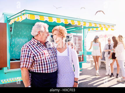 Ein Lächeln auf den Lippen zärtlich Senior paar Unternehmer außerhalb sonnigen Essen Warenkorb Stockfoto