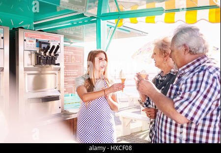 Lächelnden jungen Frau Eis senior Paar außerhalb essen Warenkorb Stockfoto