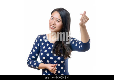 Schöne chinesische Frau im blauen Kleid mit Polka Dots gestikulieren Liebe Zeichen mit den Fingern Stockfoto