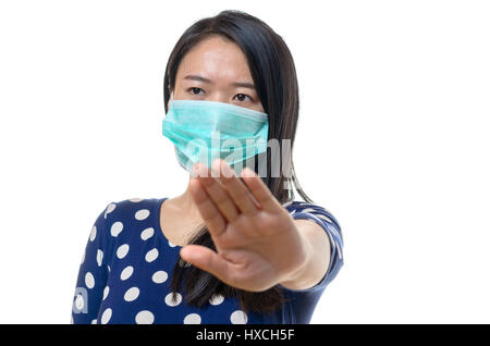 Junge Chinesin in eine Gesichtsmaske Halt Geste mit der Hand machen, wie sie Menschen zu bleiben Weg zur Vermeidung von Kontamination durch eine ansteckende Krankheit fragt Stockfoto