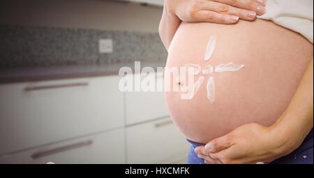 Digital Composite schwangeren Frau Mittelteil mit Sonnencreme auf Bauch in unscharfen Küche Stockfoto