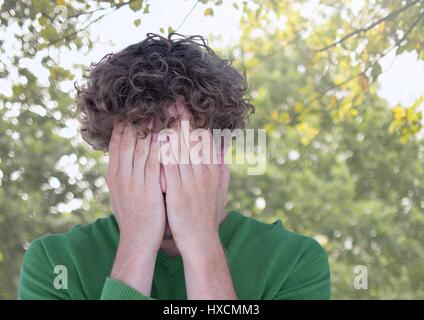 Digitalen Verbund aus verärgert betonte Mann in Händen unter Bäumen versteckt Stockfoto