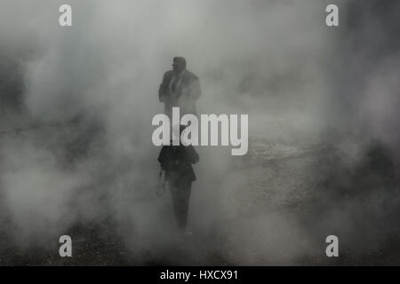 London UK 27. März 2017. Ein Fotograf und seine formell gekleidet, männliche Thema gemeinsam bei einem Fotoshooting in dichten, wirbelnden Nebel Bankside in London. Bildnachweis: Patricia Phillips / Alamy Live News Stockfoto