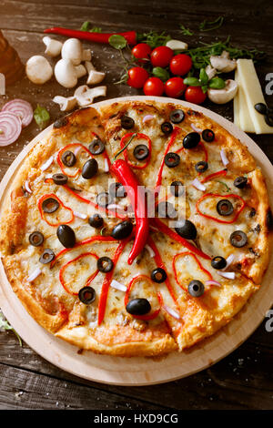 Käse-Pizza mit frischen Paprika und Zutaten auf Holztisch Stockfoto