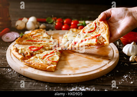 Stück Pizza in Frau mit der hand über den Tisch mit pizza Stockfoto