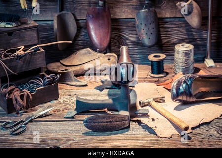 Schuster-Arbeitsplatz mit Werkzeugen, Schuhe und Schnürsenkel Stockfoto