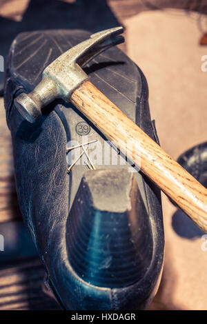 Schuster-Arbeitsplatz mit Schuhe, Schnürsenkel und Werkzeuge Stockfoto