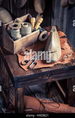 Kleine Schuster Arbeitsplatz mit Schuhe, Schnürsenkel und Werkzeuge Stockfoto