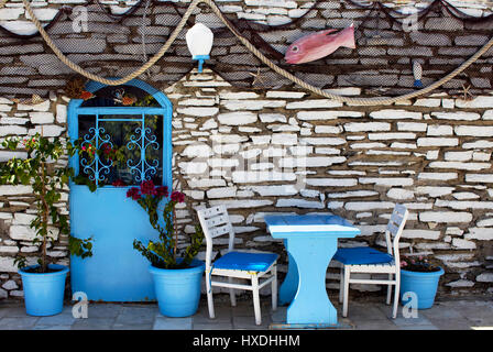 Ansicht von Fischernetzen, blaue Stühle, Tür, Töpfe und Steinmauer, die Aegean widerspiegelt / mediterranen Küsten Kultur und Lifestyle. Gefangen in der Innenstadt Stockfoto