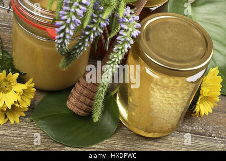 Gläser mit Honig und Blumen auf einem Tisch, Gläser mit Honig und Blumen auf einem Tisch |, Gl‰ser Mit Honig Und Blumen Auf Einem Tisch | Gläser mit Honig und Stockfoto