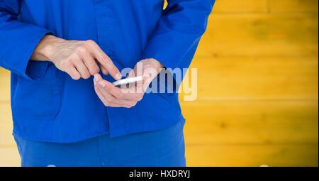 Digitalen Verbund aus Mechaniker mit Handy gegen verschwommen gelbe Holzplatte Stockfoto