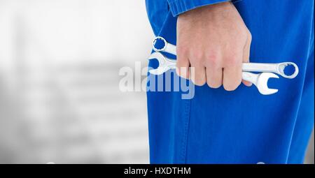 Digital Composite des Mechanikers Beine und Werkzeuge in der hand gegen die unscharfen grauen Treppen Stockfoto