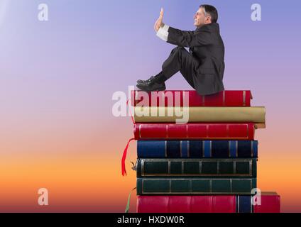 Digitalen Verbund der Geschäftsmann auf Bücher gestapelt durch Dämmerung Himmel sitzen Stockfoto