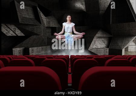 Digital Composite jungen Frau meditieren im 3d Raum mit leeren Kino Sitze Stockfoto