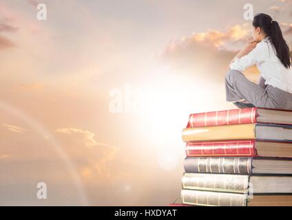 Digitalen Verbund aus Geschäftsfrau auf Bücher gestapelt, indem Sonne Wolken sitzen Stockfoto