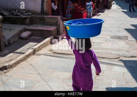 Bhaktapur, Nepal - vom 20. März 2015: Junge Mädchen mit einem Kunststoff blau Becken auf den Kopf Stockfoto