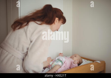 Liebevolle Mutter Babys Windel in Krippe zu Hause ändern Stockfoto