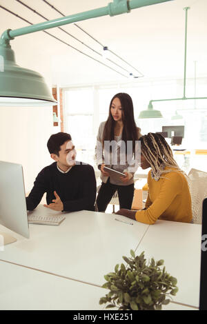Gruppe von Führungskräften diskutieren über Computer am Schreibtisch im Büro Stockfoto