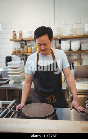 Männlichen Chef machen Pfannkuchen auf Pfanne in Großküchen Stockfoto