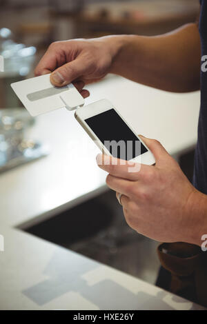 Bild des Barista Klauen Kreditkarte in das Mobiltelefon im Café verbundene Gerät beschnitten Stockfoto