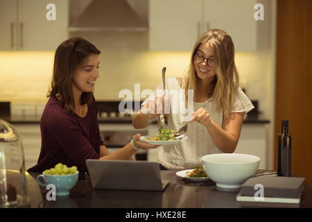 Glückliche Freunde mit Laptop beim Frühstück in der Küche zu Hause Stockfoto