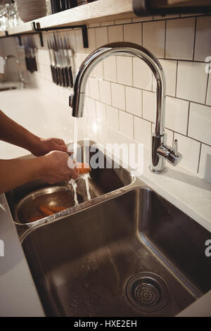 Koch waschen Karotte unter dem Wasserhahn im Profi-Küche Stockfoto