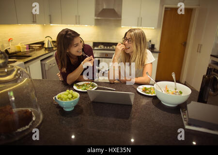 Glückliche Freunde mit Laptop beim Frühstück in der Küche zu Hause Stockfoto