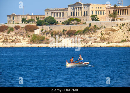 Birgu, MALTA - 24. Juli 2015: Zwei jungen Rudern im Boot auf dem Wasser des Grand Harbour mit Blick auf die Villa Bighi (Bighi Royal Naval Hospital) auf Stockfoto