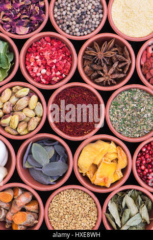 Kochzutaten. Kräutern, Gewürzen, Nüssen und Samen in Runde Terrakotta Töpfe Muster Stockfoto