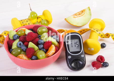 Salat von frischen Früchten, Blutzuckermessgerät mit Ergebnis der Zuckergehalt, Maßband und Hanteln für Fitness, Konzept der Diabetes, Sport, Diät, abnehmen, Gesundheit Stockfoto
