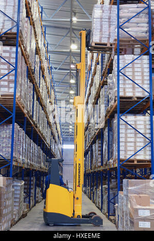St. Petersburg, Russland - 21. November 2008: Gelbe Fußgänger Stapler hebt Paletten mit Kartons in Regalen. Gabelstapler Paletten LKW Aufzüge Palette in engen Stockfoto