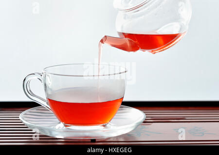 Gießen Tee in ein farbloses Glas Café Stil Tasse von Teekanne Stockfoto