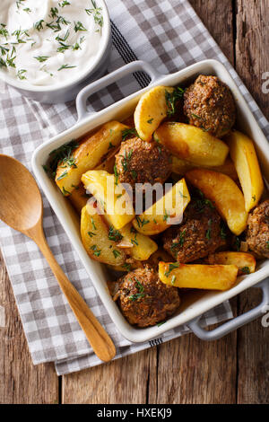 Frikadellen mit Kartoffeln in eine Auflaufform Gericht und Sauerrahm Nahaufnahme auf einem Tisch. Vertikale Ansicht von oben Stockfoto