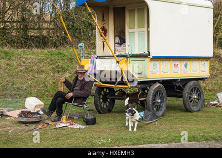 Eine ältere Reisende und sein Pferd und zwei Hunde sitzen außerhalb seiner traditionellen Wagen von einem Kohlenbecken Stockfoto