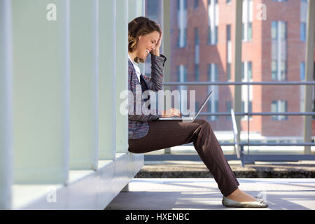 Seitenansicht einer glücklich Business-Frau mit Laptop draußen Stockfoto