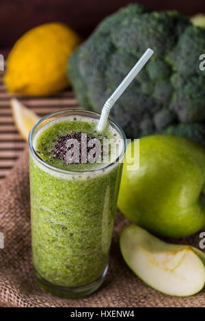 Brokkoli-Smoothie in Glasschüssel auf hölzernen Hintergrund mit Zitrone und Apfel. Stockfoto